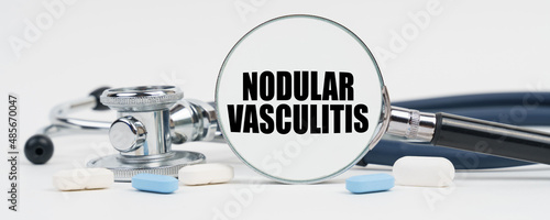On a white surface are pills, a stethoscope and a magnifying glass inside which is written - Nodular vasculitis photo