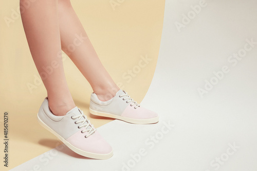 Woman legs in stylish pastel sneakers isolated on beige background, space for text