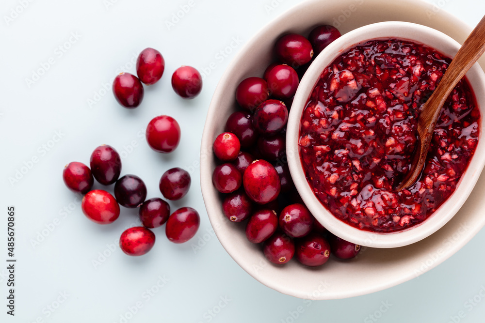 Cranberries in white bowl on pastel background. Cranberries in white bowl on pastel background.