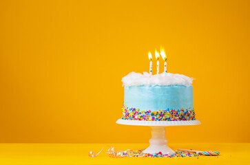 Blue Birthday Cake with three Candles over a yellow Background