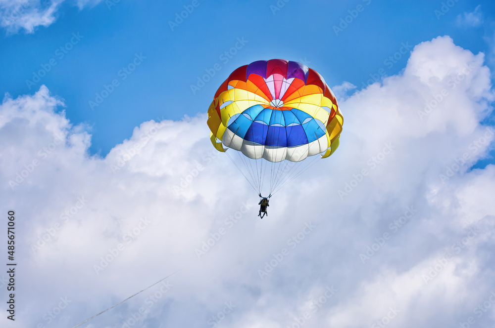 Paragliding using a parachute on background of blue cloudy sky. Paragliding using a parachute on background of blue cloudy sky.