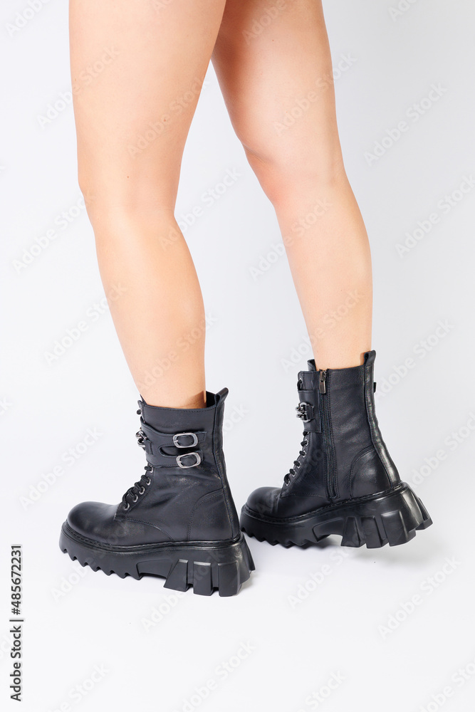 Legs of a woman in black leather boots from a new collection on a white background, legs of a girl in fashionable leather boots spring 2022. Legs of a woman in black leather boots from a new collection on a white background, legs of a girl in fashionable leather boots spring 2022.