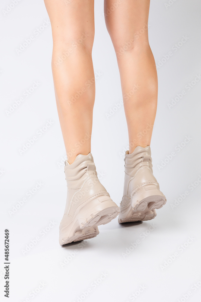 Female legs in beige leather shoes from the new collection on a white background female legs in fashionable shoes made of eco-leather spring 2022. Female legs in beige leather shoes from the new collection on a white background female legs in fashionable shoes made of eco-leather spring 2022.