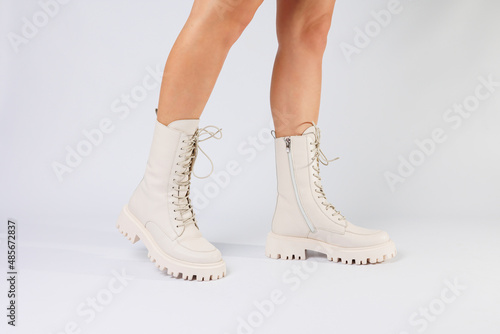 Woman's legs in a collection of fashionable leather white shoes on a white background, spring collection of women's shoes