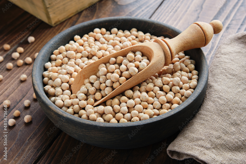 Raw chickpeas in bowl. Chickpeas in bowl and scoop on wooden table. Raw chickpeas in bowl. Chickpeas in bowl and scoop on wooden table.