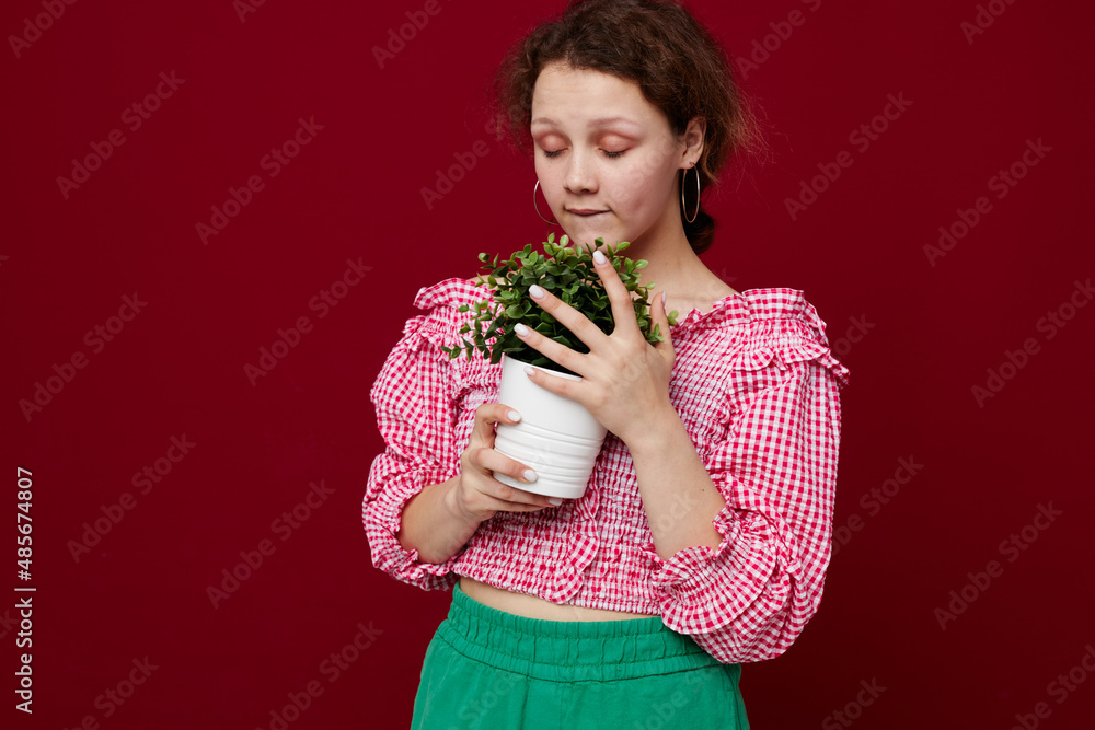 beautiful woman in pink blouse is posing with a plant in white pot close-up beautiful woman in pink blouse is posing with a plant in white pot close-up