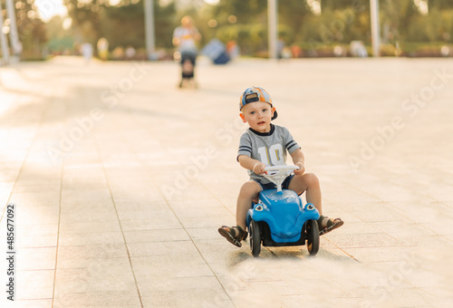 child with a toy car outdoors. The boy rides on a typewriter in the park.Active rest with children on a warm summer day. © Shopping King Louie