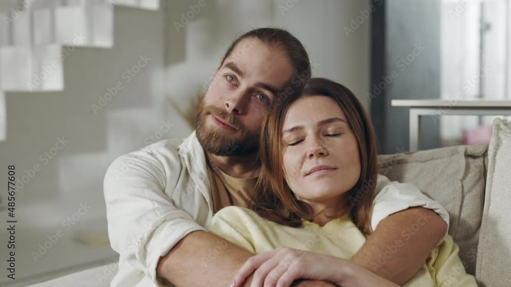Two loving people sitting in strong hugs on cozy sofa Two loving people sitting in strong hugs on cozy sofa