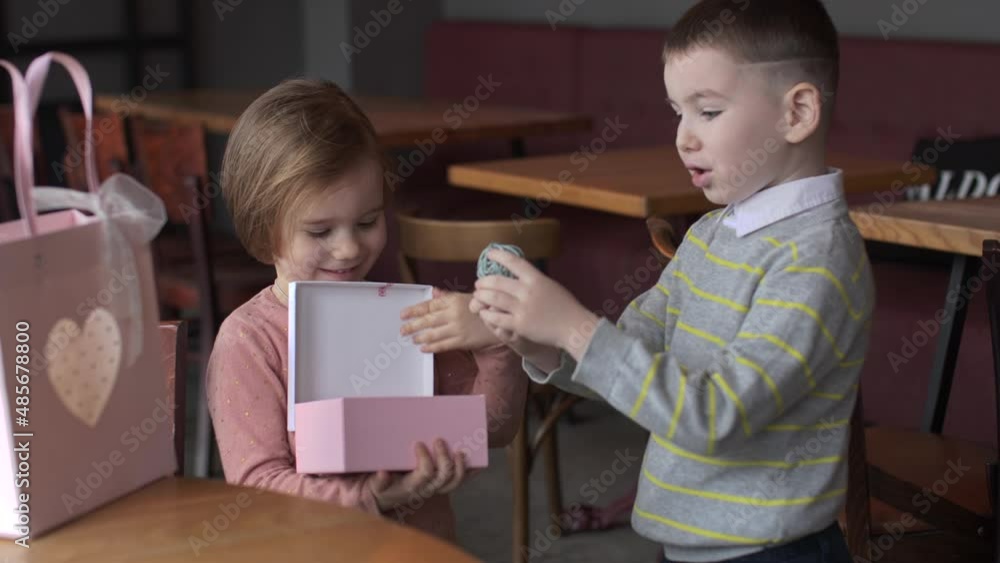 little boy and girl in cafe open a gift for valentine's day little boy and girl in cafe open a gift for valentine's day