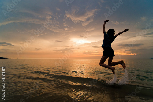 A young woman jumping for joy and celebrating on the beach at sunset., Thai Islands at Koh Samui, Thailand, Southeast Asia