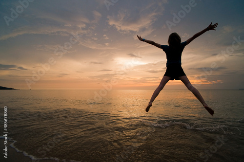 A young woman doing a star jump  enjoying her freedom on the beach at sunset.  Thai Islands at Koh Samui  Thailand  Southeast Asia