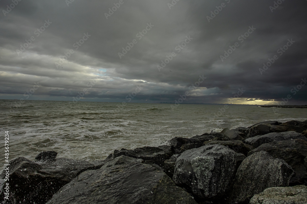 dramatic sky over the black sea with waves, clouds and stones