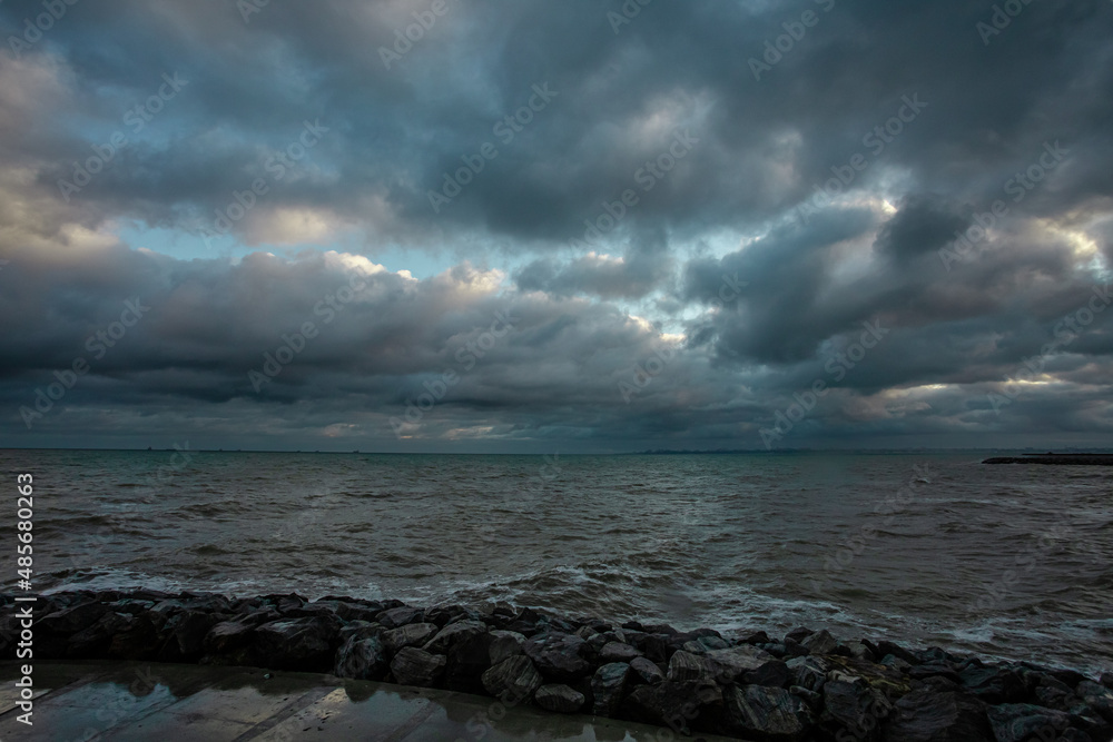 dramatic sky over the black sea with waves, clouds and stones
