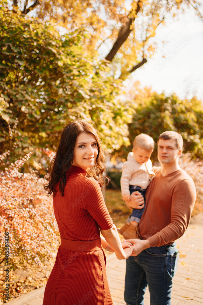 a family with a small child on an autumn walk around the city. a family with a small child on an autumn walk around the city.