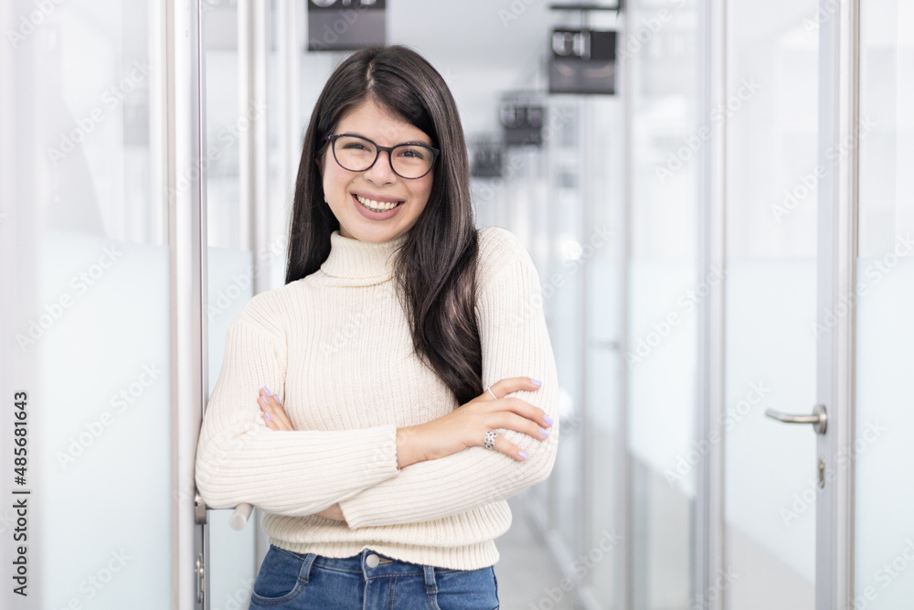 White woman standing on a office corridor smiling with crossed arms White woman standing on a office corridor smiling with crossed arms