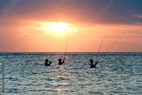 Fisherman fishing at Sunset in teh ocean on Sengiggi Beach, silhouetted against the sun, Lombok, Indonesia, Asia, background with copy space