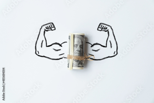 The concept of a strong world currency. Muscle hands with a bunch of us dollars money.