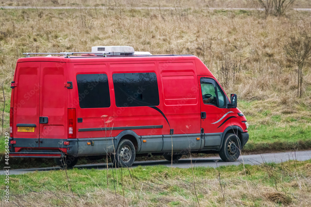 a long wheel base Iveco Daily 355 2.3 HPI red van driving along a country road