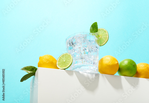 Fresh lemons and lime cocktail with ice cubes and fresh basil or mint. Cold summer or spring drink made with citrus fruits mediterranean style. Refreshing lemonade drink or lemon water. 