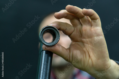 A bicycle mechanic in the workshop holds a frame from an old bicycle in his hands. Checking bicycle parts for wear, replacing broken parts. The face of a guy in a shirt on a black background