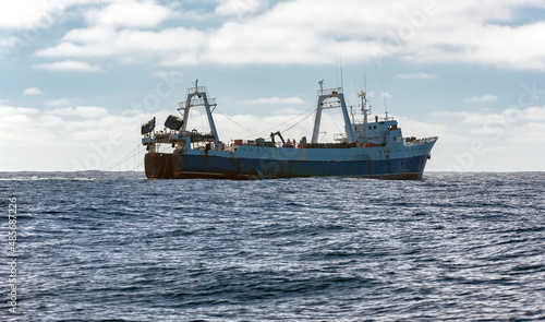 Commercial fishing trawler is fishing for marine fish and seafood in oceanic waters.