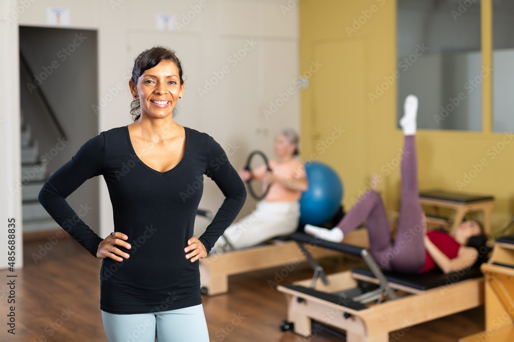 Portrait of a smiling confident latin american woman standing in a fitness studio during a Pilates workout