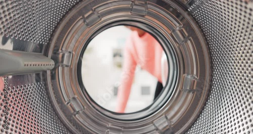 Shot from inside washing machine drum, woman opens door and packs colorful clothes inside, puts t-shirts, jeans in wash photo