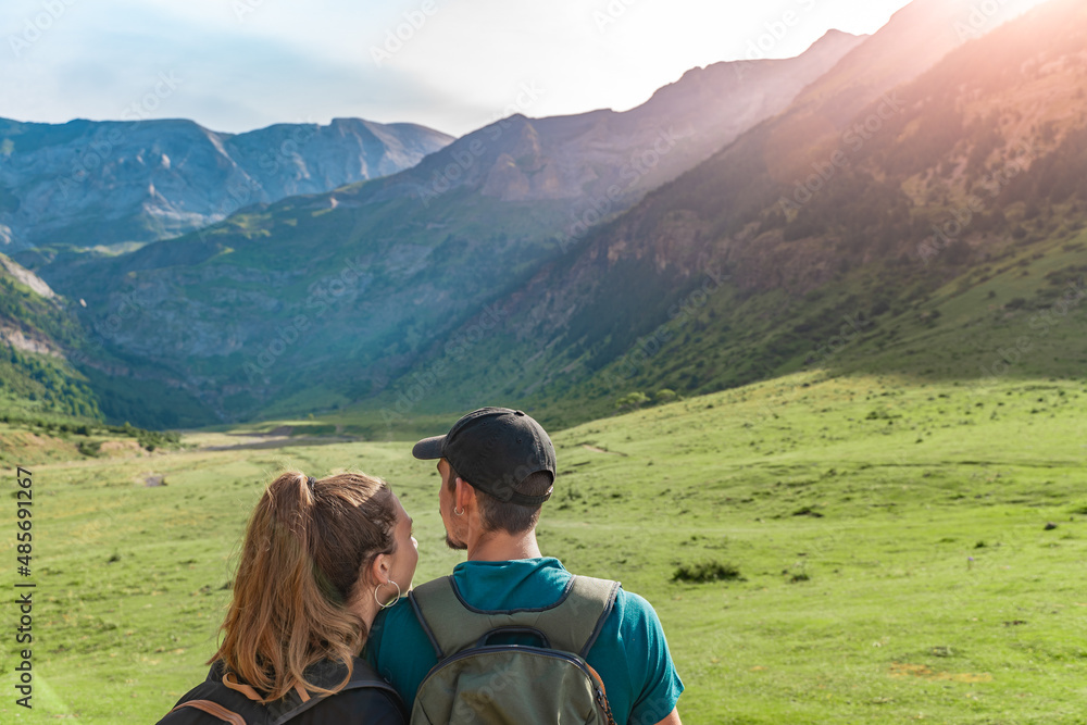 Young Couple in a beautiful valley between mountains during the sunset. Discovery Travel Destination and Freedom Concept.