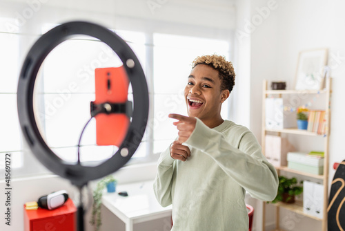 Young male creator recording online media video on his room - Millennial guy streaming online and sharing social media content by mobile phone app network - New trends for millennial people concept photo