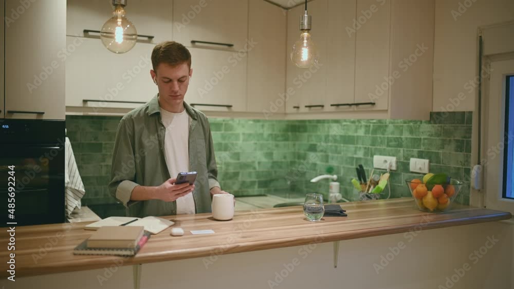 Redhead man drinking coffee and using smartphone and ipods in the kitchen at home Redhead man drinking coffee and using smartphone and ipods in the kitchen at home