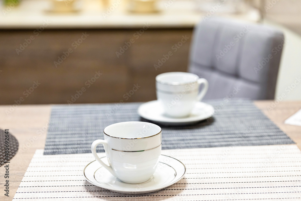 Two tea or coffee cups with saucers on the kitchen table. The topic of waiting for breakfast Two tea or coffee cups with saucers on the kitchen table. The topic of waiting for breakfast
