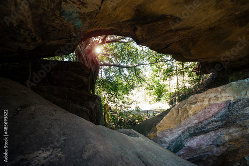 A cave with light passing through it resembles a baby bird. There is a golden Buddha statue inside the cave. It is one of the tourist attractions in Kalasin Province, Thailand. photo