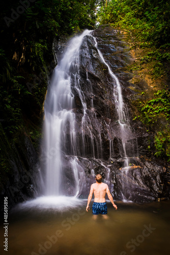 Tourist under Cucharillos Waterfall in the Mashpi Cloud Forest area of the Choco Rainforest, Pichincha Province, Ecuador, South America