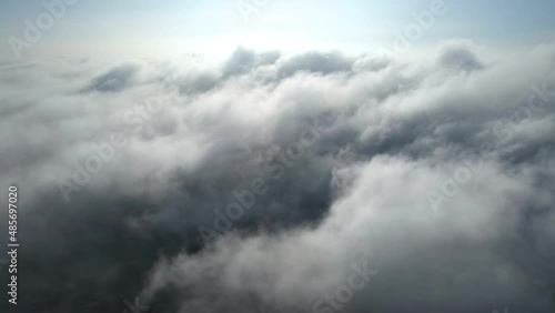 Aerial shot of flying over a layer of soft clouds at dawn
