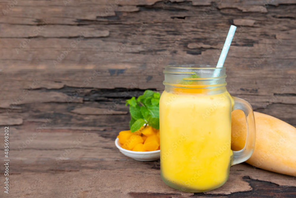Fototapeta premium Mango juice fruit smoothies yogurt drink yellow healthy delicious taste in a glass slush for weight loss on wooden background.