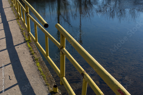 The broken fence on the bridge over the river. Dangerous and damaged bridge for pedestrians and cars