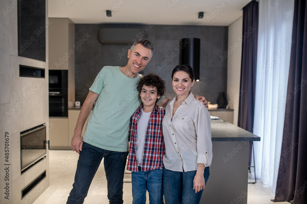 Man hugging boy and woman looking at camera Man hugging boy and woman looking at camera