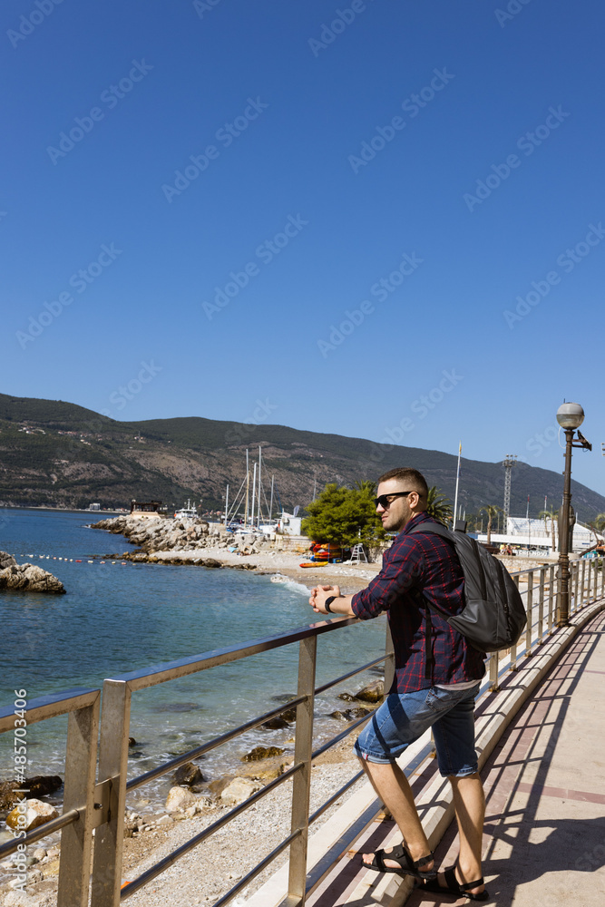 Man on the Promenade looks at yachts  in well-preserved medieval town Herceg Novi near Bay of Kotor, the Adriatic Sea in southwestern Montenegro.  Travelling and leasure concept. Recreation area