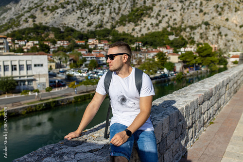 Man sits on Kotor old wall Fortification in Montenegro. Unesco world heritage. Europe travel site. Vacation concept.  Tourism in adriatic sea. Serbian history of balkans, fort and port buildings.. © Евгения Жигалкина