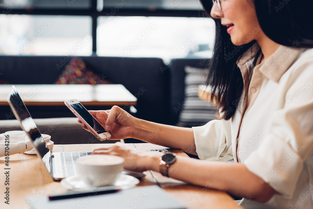 Lifestyle freelance working woman and laptop computer he using smartphone for check status in coffee cafe shop