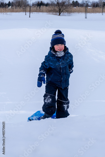 Young boy enjoying the winter while carrying a winter sled. High quality photo