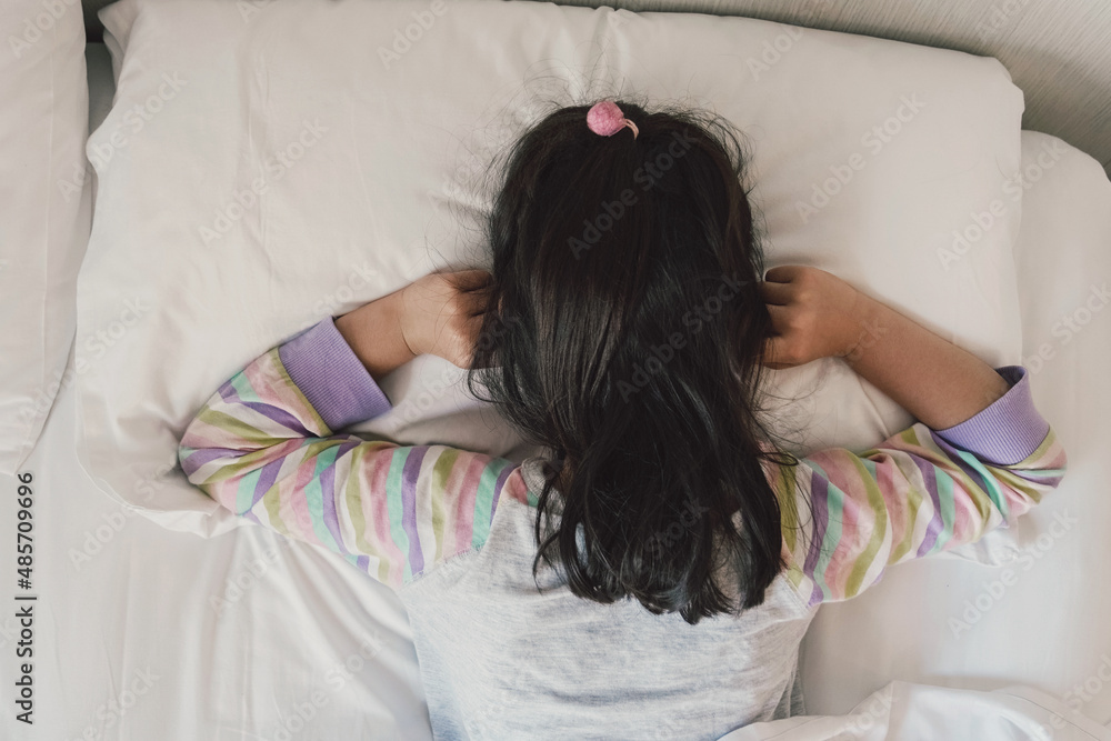 Girl covering ears with his fingers in bed, ADHD, sleep disorder