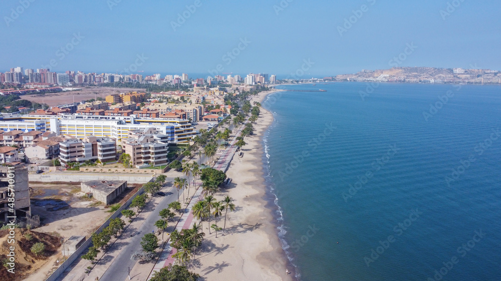 Aerial photos from a drone to a beach in Venezuela, where you can see beaches, residential areas, roads, trees, palms, sand, blue sky, residential hill, pools, roads, waves.