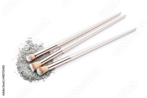 Makeup brushes and loose eye shadow on white background