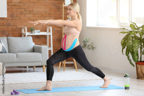 Pregnant woman with applied kinesio tape training at home