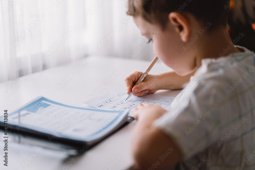 Distance learning education. Back to school. Cute kid boy studying at home and doing school homework. Thinking child sitting at table Distance learning education. Back to school. Cute kid boy studying at home and doing school homework. Thinking child sitting at table