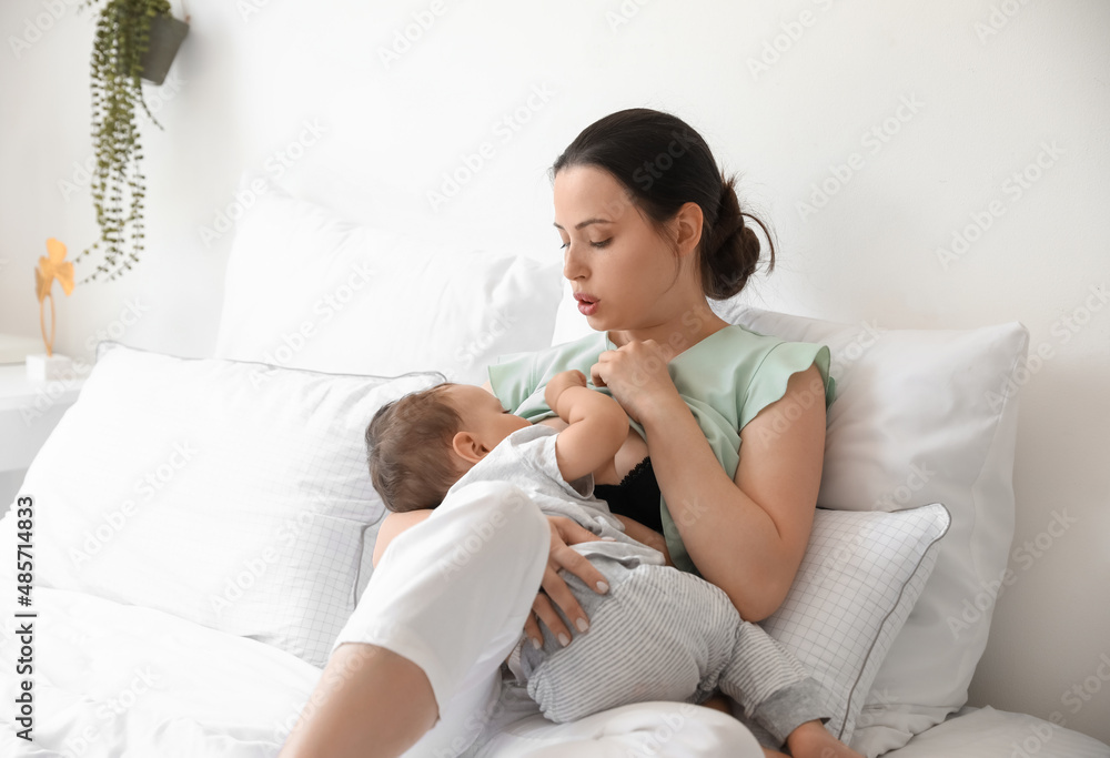 Young mother breastfeeding her adorable baby on bed Young mother breastfeeding her adorable baby on bed