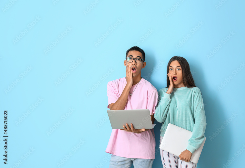 Shocked young couple with laptops on blue background Shocked young couple with laptops on blue background