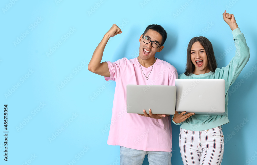 Happy young couple with laptops on blue background Happy young couple with laptops on blue background