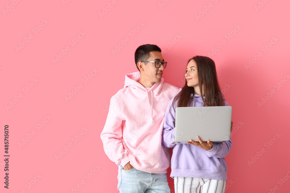 Young couple with laptop on pink background Young couple with laptop on pink background